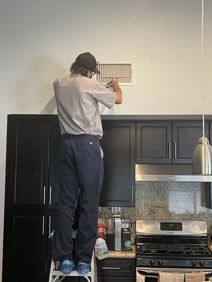 Technician inspecting an air vent during HVAC service in Charlotte